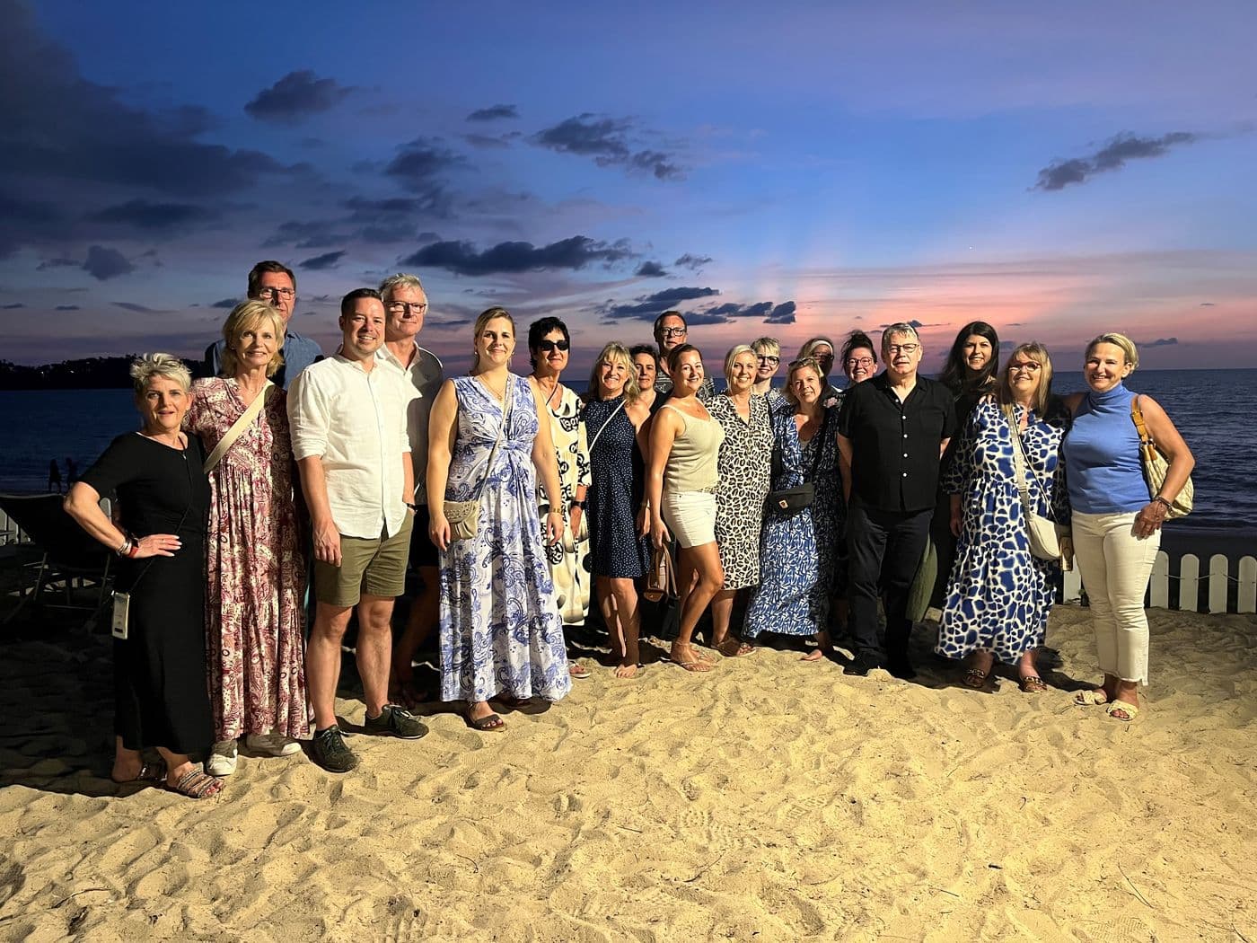 Gruppenfoto der Inhaber-Gewinnerreise nach Thailand: Inhaberin und Inhaber von HOLIDAY LAND stehen in Thailand am Strand vor dem Meer bei Sonnenuntergang.